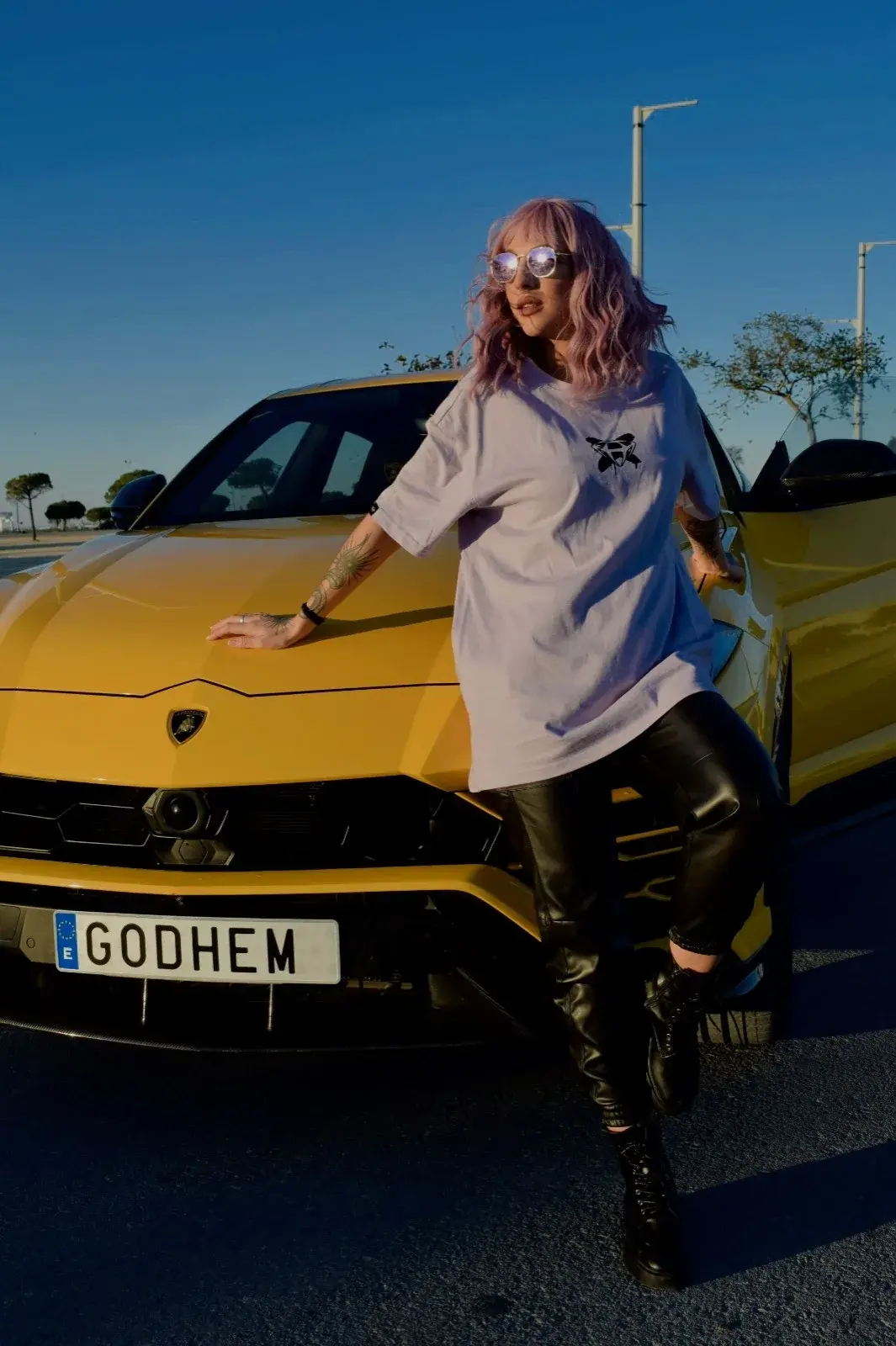 Modelo apoyada en el coche con la camiseta lavanda